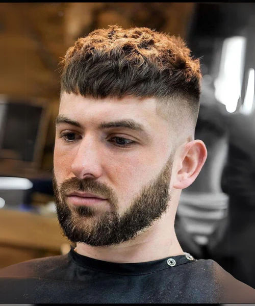 "A relaxed and youthful undercut hairstyle fade featuring a textured, messy fringe styled forward, contrasted with a subtle low fade for a cool and effortless look."