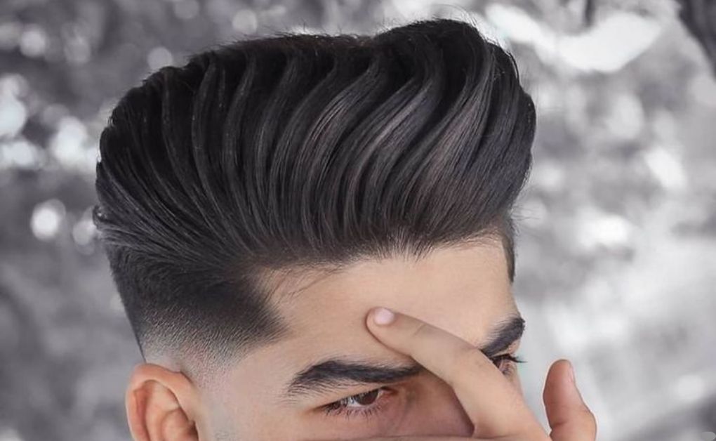 "A sleek and functional undercut hairstyle fade featuring a man bun on top, paired with a sharp fade that provides a clean-cut look even with long hair."
