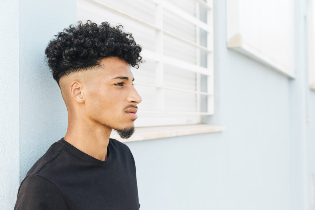 Men’s hairstyle featuring short starter locs on top with a clean drop fade curving behind the ears.